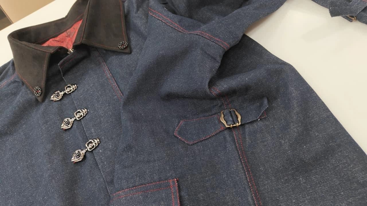 The denim garment laid out to show its considered construction, fastening details, and generous pockets.
