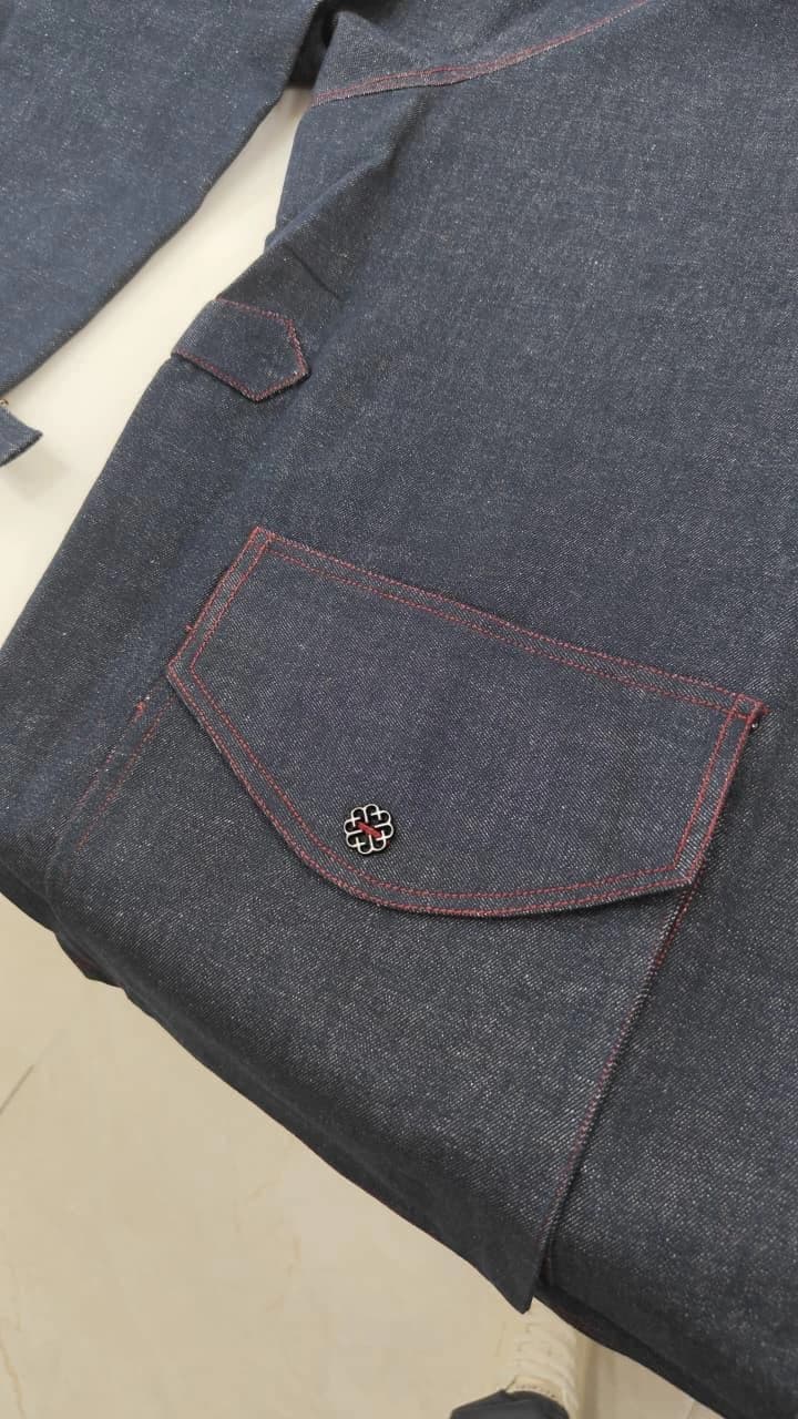 A shaped denim pocket with red double stitching and a small decorative metal fastening.